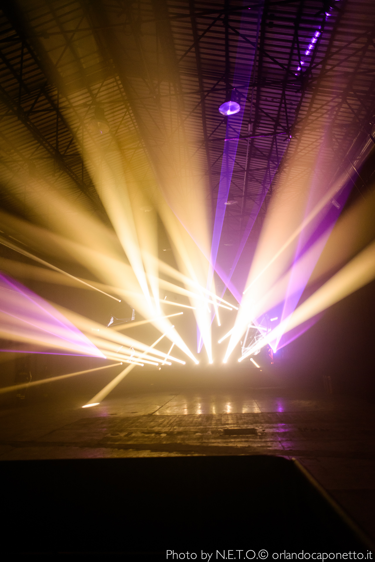 Fascio di luci colorate che si irradiano in una sala, creando un'atmosfera dinamica e vibrante.