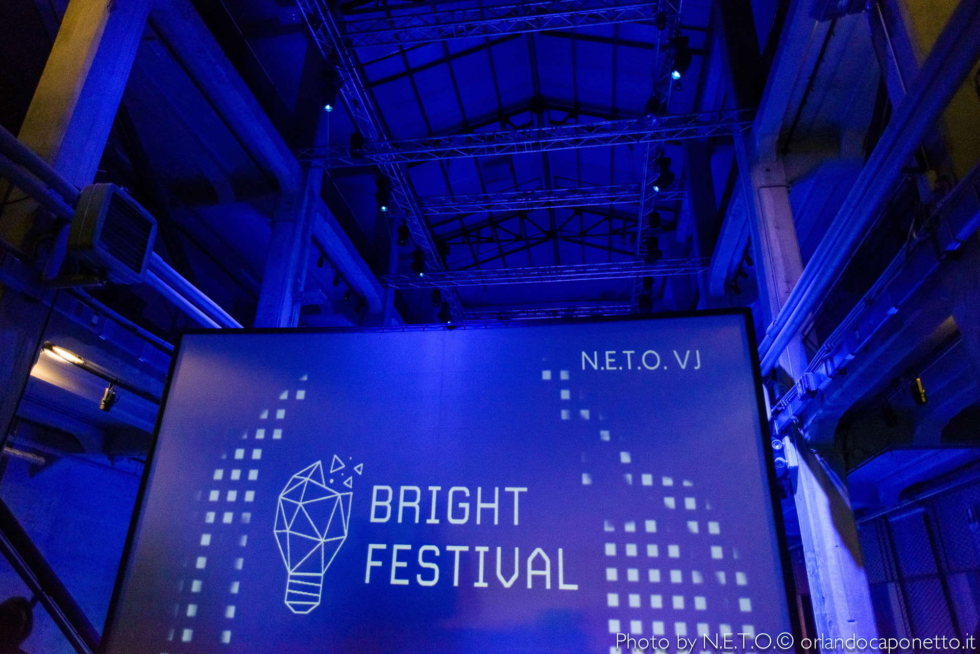 Schermo del Bright Festival con il logo di N.E.T.O.VJ, illuminato da luci blu.