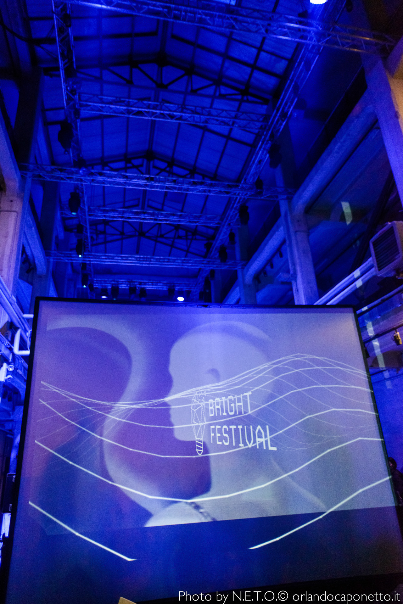 Un'immagine del Bright Festival, con uno schermo che mostra il logo dell'evento su uno sfondo blu.